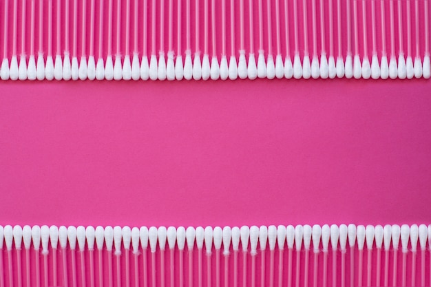 Foto la opinión superior del primer sobre los brotes del algodón puso en una línea horizontal dos en fondo rosado