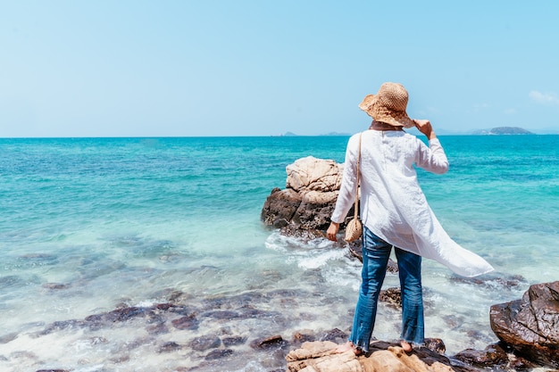 Opinión trasera la mujer asiática musulmán joven que mira del acantilado. Futuro y concepción de la investigación. Mujer feliz con las manos que se levantan en el acantilado sobre el mar. Estado de ánimo para viajar, conceptos de ganador, libertad.