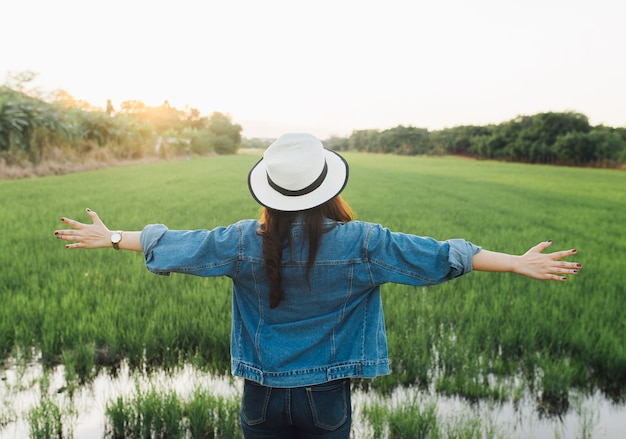 Opinión trasera la mujer joven en sombrero. Chica disfrutando de la hermosa naturaleza con puesta de sol.