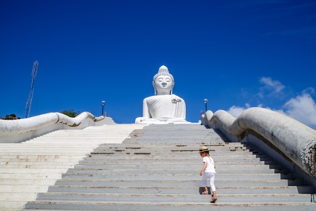 Opinión trasera la niña que se coloca cerca de la estatua grande de Buda en Phuket, Tailandia.