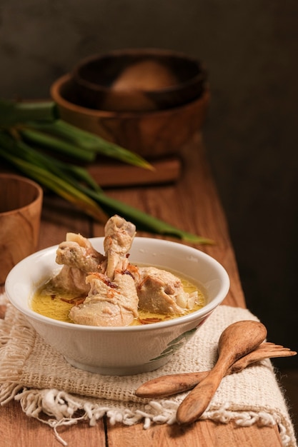 Opor ayam é servido em uma mesa de madeira. opor é uma comida tradicional indonésia feita de frango cozido com molho de leite de coco