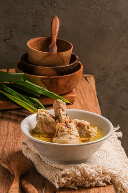 Opor Ayam se sirve en una mesa de madera. Opor es una comida tradicional de Indonesia hecha de pollo cocinado con salsa de leche de coco.