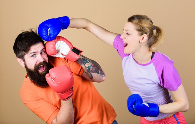 La oportunidad puede golpear el nocaut y el entrenamiento de pareja de energía en guantes de boxeo Mujer feliz y hombre barbudo entrenando en ropa deportiva de gimnasio Entrenamiento de lucha con el entrenador golpeando deporte Éxito nocaut