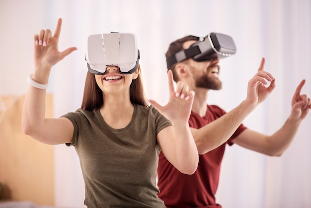 Oportunidades de realidad virtual. Mujer alegre alegre alegre moviendo las manos mientras sonríe y se pone los auriculares VR