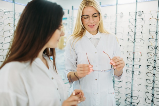 Foto Óptico muestra gafas al cliente en la tienda de óptica