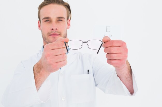 Un óptico que muestra gafas al lado de un examen ocular.