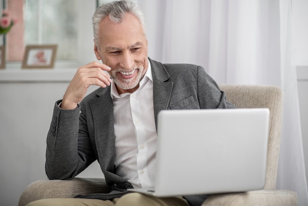 Optimismo. Hombre alegre que siente felicidad mientras mira la pantalla de su computadora portátil y levanta la mano derecha