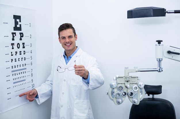 Optometrista apuntando a la tabla optométrica