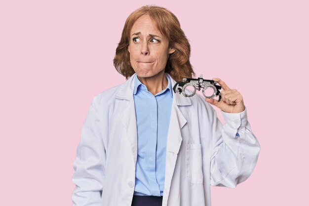 Foto optometrista caucásico de mediana edad en el estudio confundido se siente dudoso e inseguro