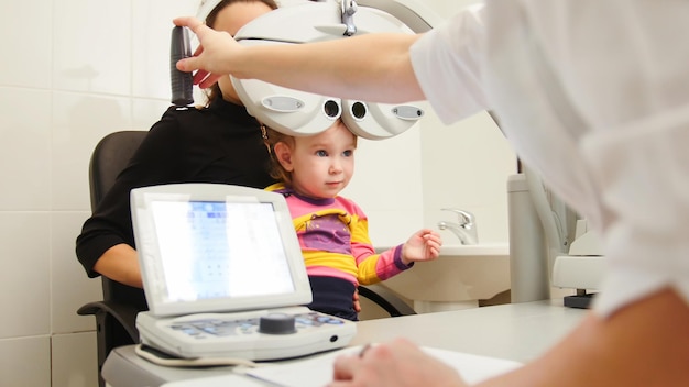 Optometrista en la clínica comprobando la visión de la niña - Oftalmología infantil, horizontal