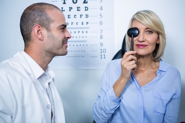 Foto optometrista examina paciente femenino con equipo médico