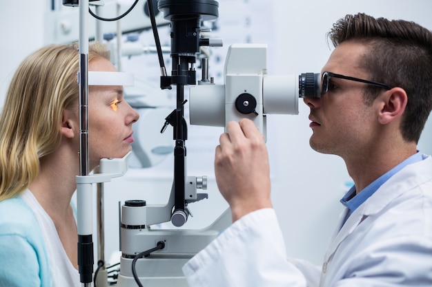 Optometrista examinando paciente femenino en lámpara de hendidura