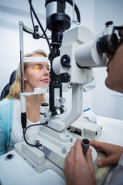 Optometrista examinar paciente do sexo feminino na lâmpada de fenda
