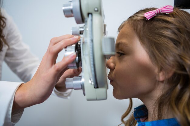 Optometrista fêmea que examina paciente novo no phoropter