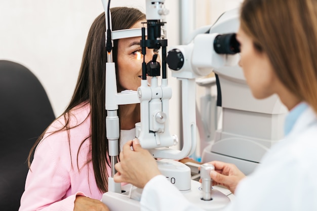 Optometrista femenina comprobando la visión del paciente en la clínica oftalmológica. Concepto médico y sanitario.