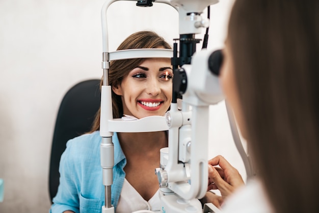 Optometrista femenina comprobando la visión del paciente en la clínica oftalmológica. Concepto médico y sanitario.