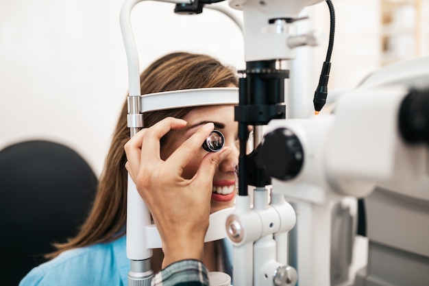 Optometrista femenina comprobando la visión del paciente en la clínica oftalmológica. Concepto médico y sanitario.