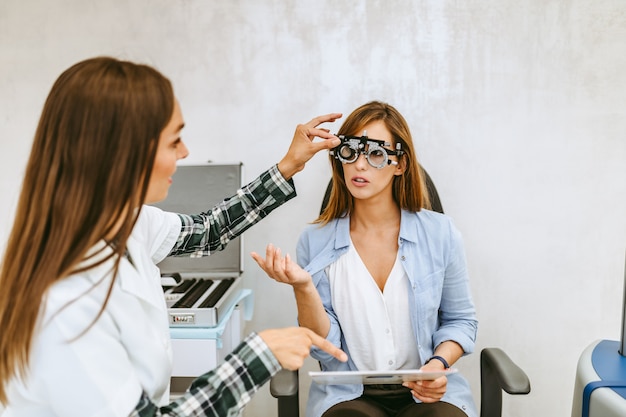 Optometrista femenina comprobando la visión del paciente en la clínica oftalmológica. Concepto médico y sanitario.