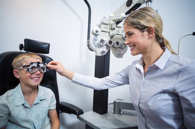 Optometrista femenino examinando paciente joven con foróptero