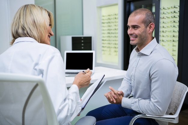 Optometrista feminina falando com paciente do sexo masculino