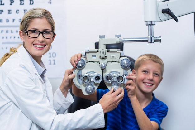 Optometrista y paciente joven sonriendo mientras se somete a un examen ocular