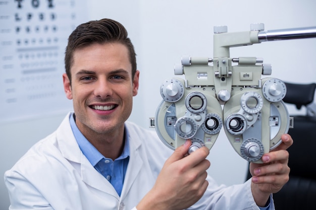 Optometrista sonriente que ajusta el foróptero