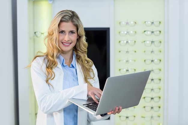 Optometrista usando laptop en clínica oftalmológica