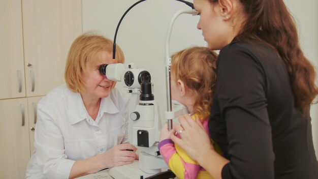 Optometristin prüft Sehkraft bei kleinem Mädchen - Augenheilkunde des Kindes, Tele