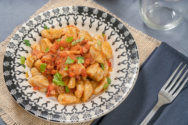 Ñoquis italianos caseros con salsa roja servidos en un plato decorado.