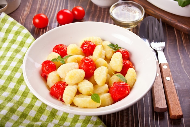 Ñoquis italianos caseros con tomate cherry en la mesa de madera