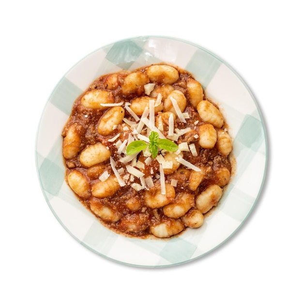 Ñoquis de pasta italiana en un plato con salsa boloñesa aislado sobre fondo blanco.