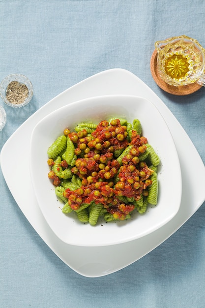 Ñoquis de pasta italiana tradicional fresca de Cerdeña con espinacas y salsa de tomate con guisantes verdes pasta de primavera para las vacaciones de semana santa.