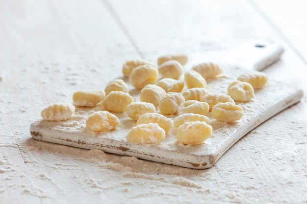 Ñoquis de patata italiana cruda casera tradicional sobre fondo blanco de madera