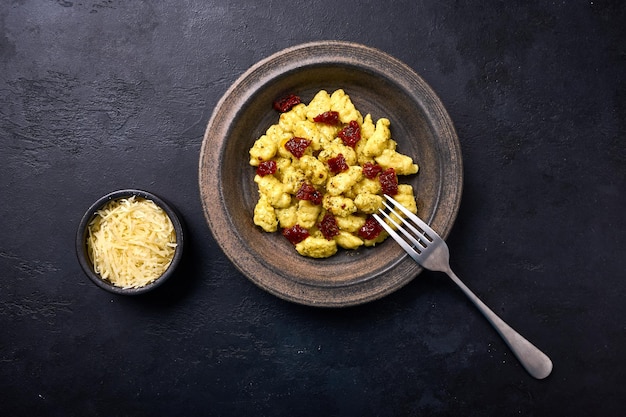 Ñoquis de patata italianos tradicionales con parmesano y tomates secos en placa de cerámica con tapa de horquilla