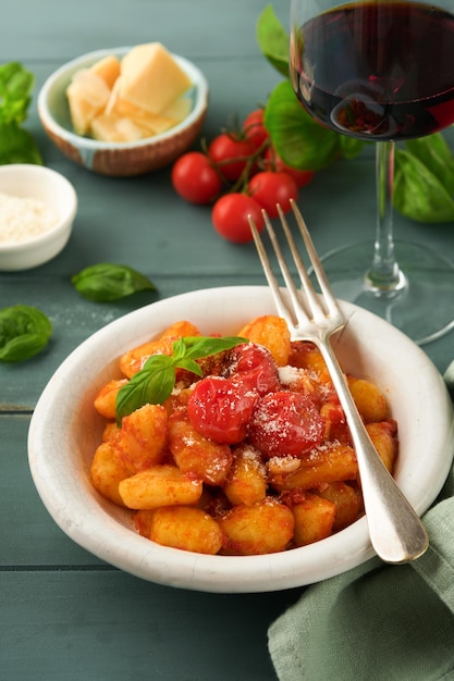 Ñoquis de patata Ñoquis de patata caseros tradicionales con salsa de tomate, albahaca y queso parmesano sobre fondo de mesa de cocina rústica turquesa Comida italiana tradicional Vista superior