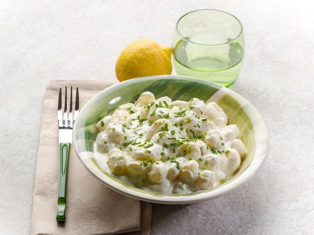 Ñoquis con salsa de crema de cebollino y limón rallado