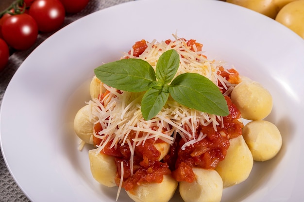 Ñoquis con salsa de tomate ecológico natural sin pesticidas con queso parmesano rallado y hojas de albahaca.