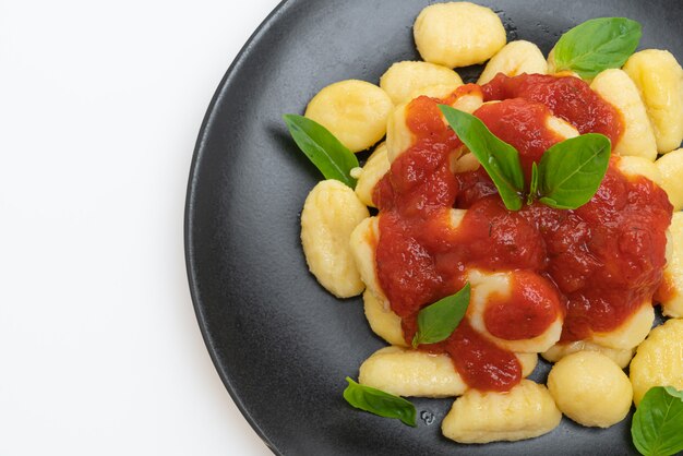 Ñoquis en salsa de tomate con queso aislado en blanco