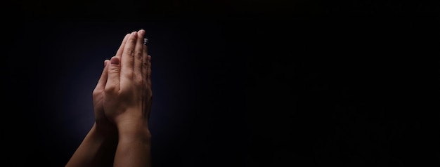 Oração de mãos sobre fundo escuro, conceito de fé e religião, layout panorâmico