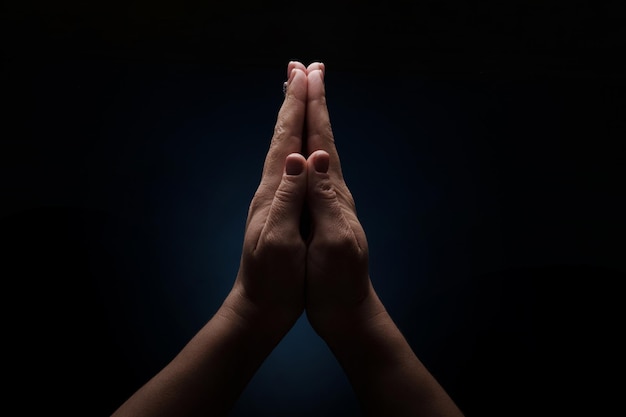 Oração de mãos sobre fundo escuro, conceito de fé e religião