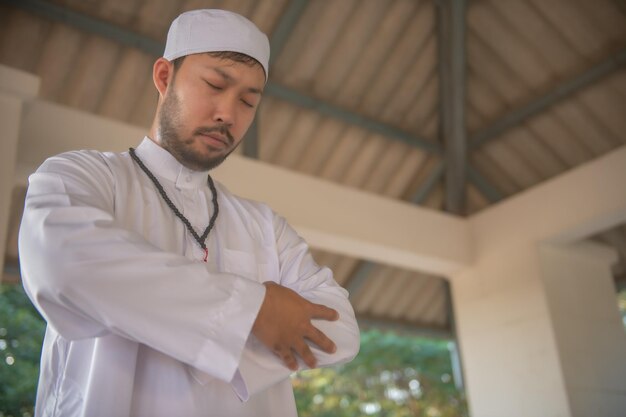 Oração do homem islâmico asiáticoJovem muçulmano rezandoConceito do festival do Ramadã