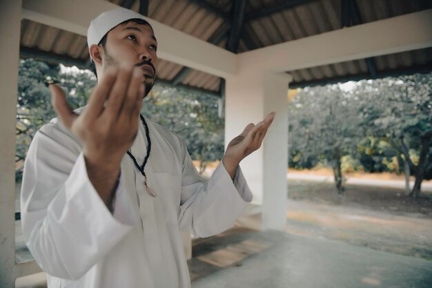 Oração do homem islâmico asiáticoJovem muçulmano rezandoConceito do festival do Ramadã