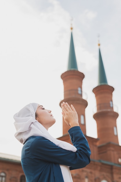 La oración de la mujer musulmana usa el hijab en ayunas reza a allah en el fondo de la mezquita