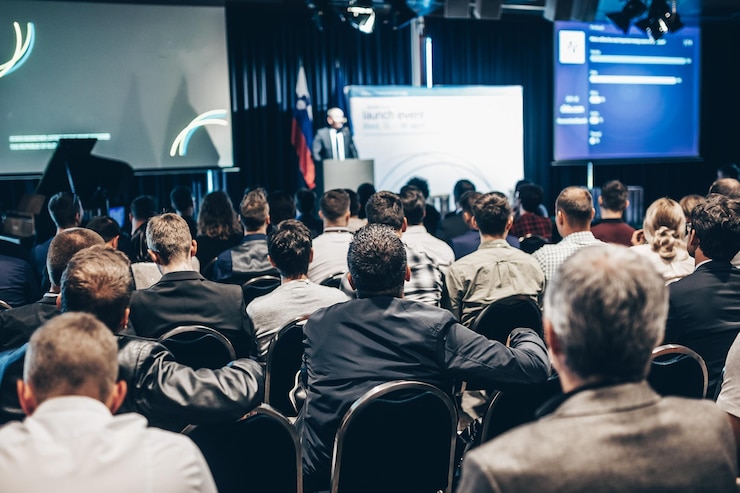 Foto orador dando una charla en la sala de conferencias en el evento de negocios vista trasera de personas irreconocibles en aud