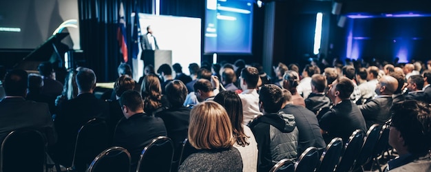 Orador dando una charla en la sala de conferencias en el evento de negocios vista trasera de personas irreconocibles en aud