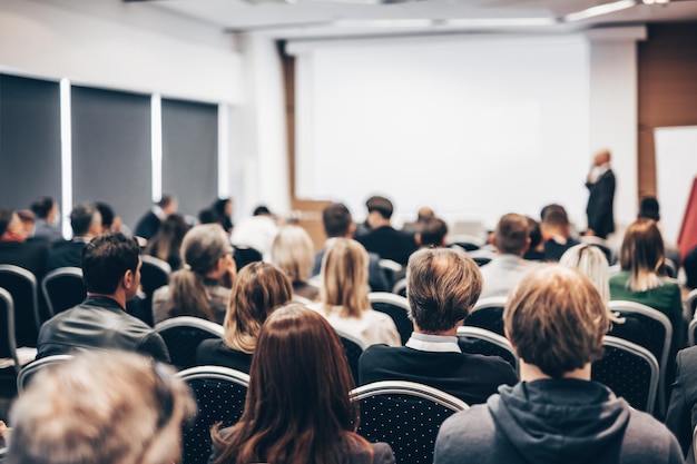 Orador dando una charla en la sala de conferencias en un evento de negocios vista trasera de personas irreconocibles en