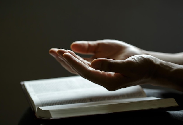 Orando com as mãos O homem reza com as mãos juntas sobre uma Bíblia Sagrada No conceito cristão de fé