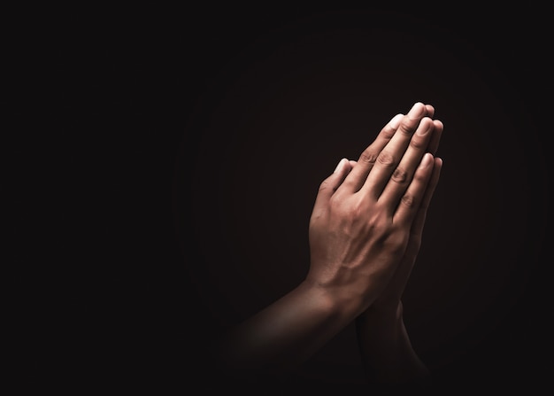 Orando manos con fe en la religión y creencia en Dios en la oscuridad. Poder de esperanza o amor y devoción. Namaste o Namaskar manos gesto. Posición de oración.