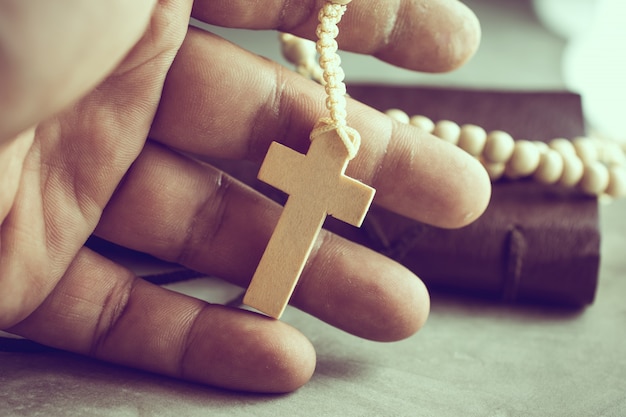 Orando las manos del pobre hombre con un rosario en la mesa de cemento oración, rosario