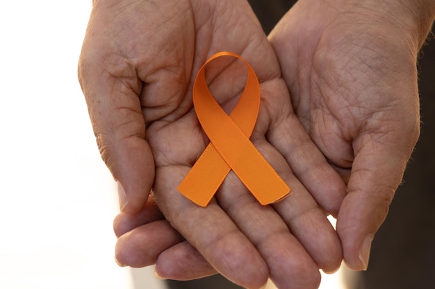 Orange agosto Campaña de Concientización sobre la Esclerosis Múltiple Mano sujetando cinta naranja